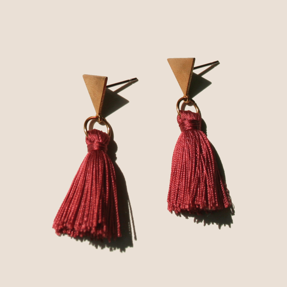 The Vibrant Berlin Stud Earrings _ Triangle stud with merlot red silk Tassel earrings on ears