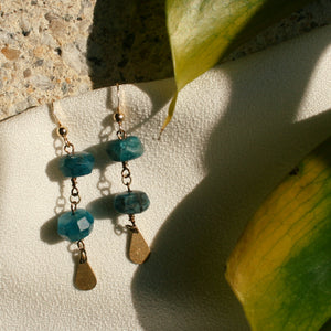 The Yoga Retreat in Bali Earrings is handcrafted from the 14K Gold-filled wire hook, natural peacock blue faceted Apatite bead with dazzling brass charms.